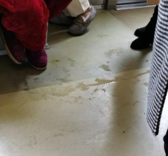 一名家长抱着一名小孩随地小便,毫不遮掩,尿液四处横流,让车厢里的