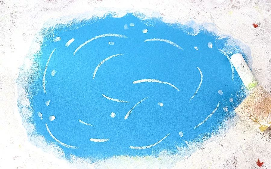 剪一张蓝色的卡纸粘贴在画面上用油画棒添加冰面上滑动的痕迹用海绵拍