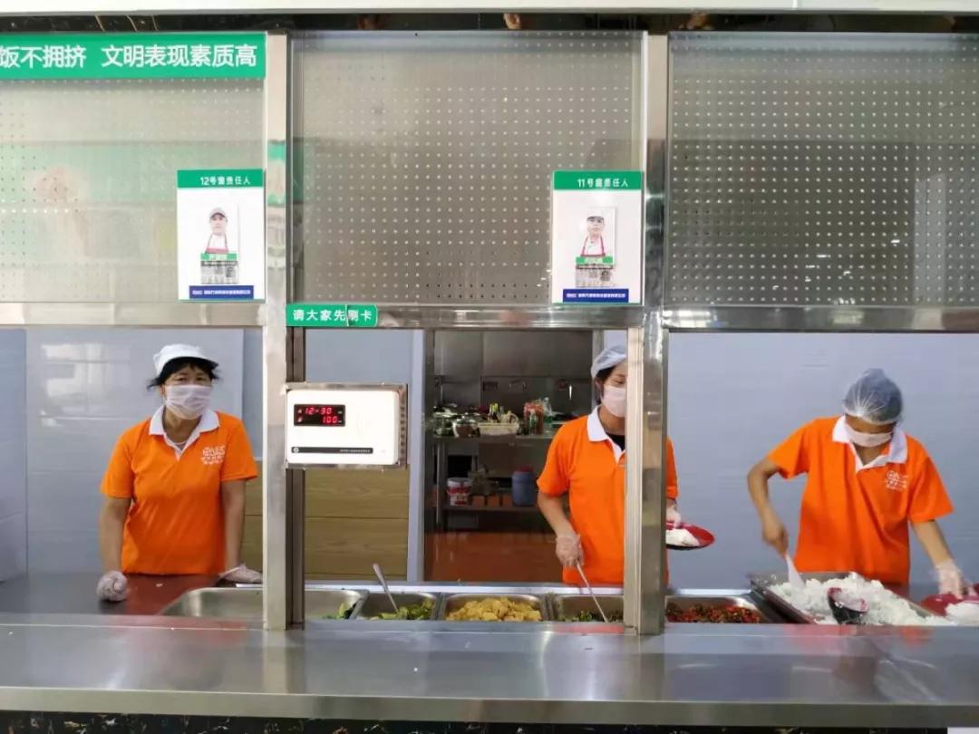 干净整洁的取餐窗口 学校食堂工作人员统一着装,佩戴口罩,帽子,手套