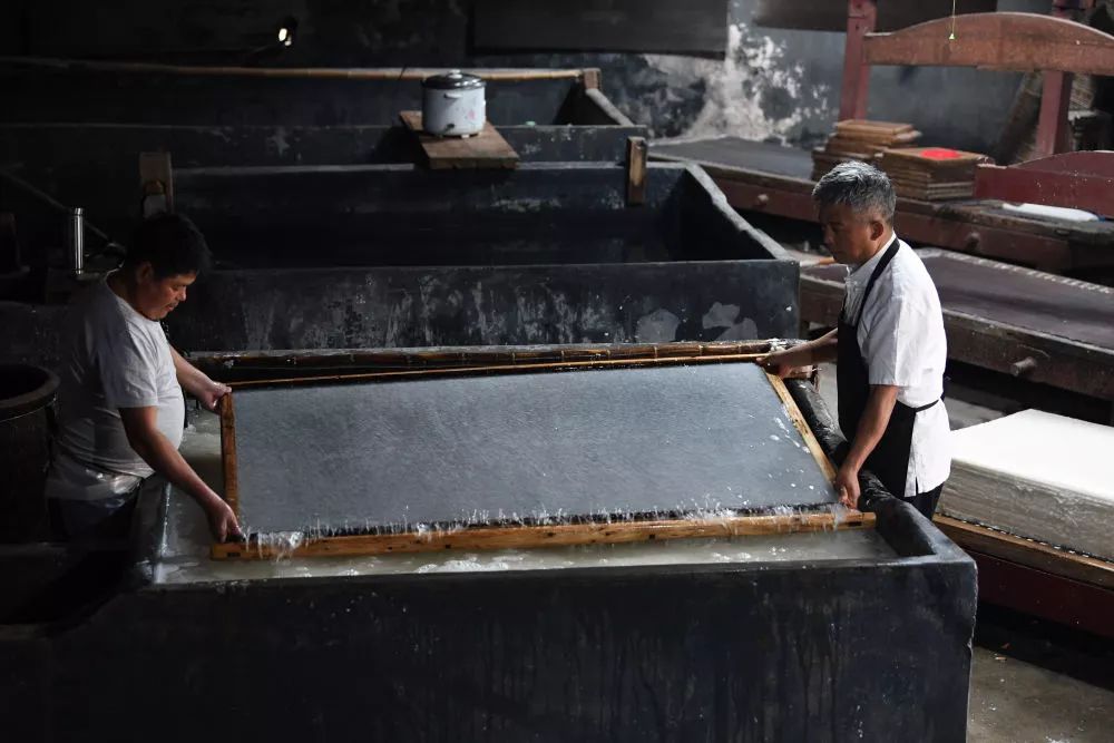 10月22日,在安徽省宣城市泾县丁家桥镇,曹建勤(右)在紫金楼宣纸厂捞纸