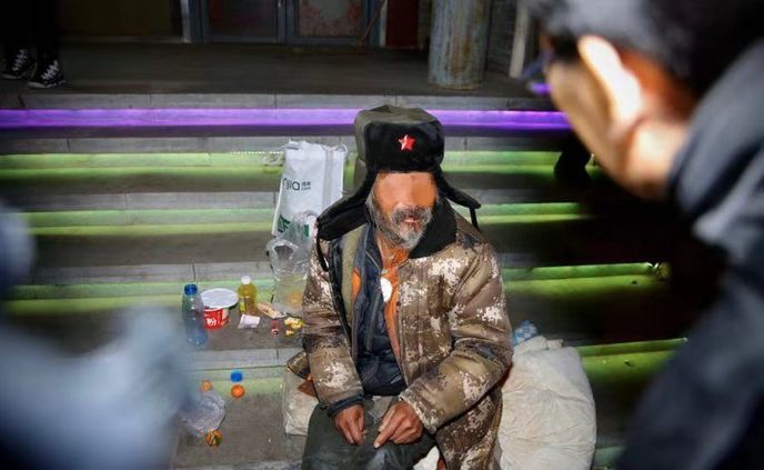 该乞讨老人不愿跟随前往救助站,救助人员从救助箱中取出军大衣送给