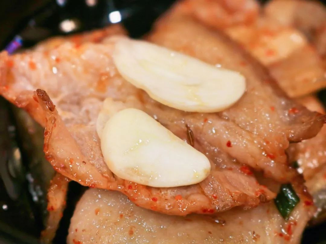 用一片烤肉包裹住蒜片,甜辣酱和辣椒粉一起塞入口中烤肉的香味最大