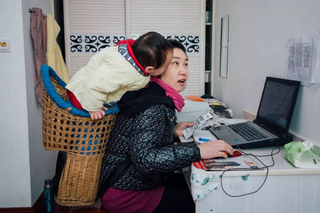 妈妈工作时,孩子在背篓里玩耍.