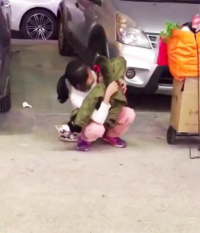 姐姐蹲着抱着妹妹,自己却穿得非常单薄,仅仅是一件白色的毛巾.