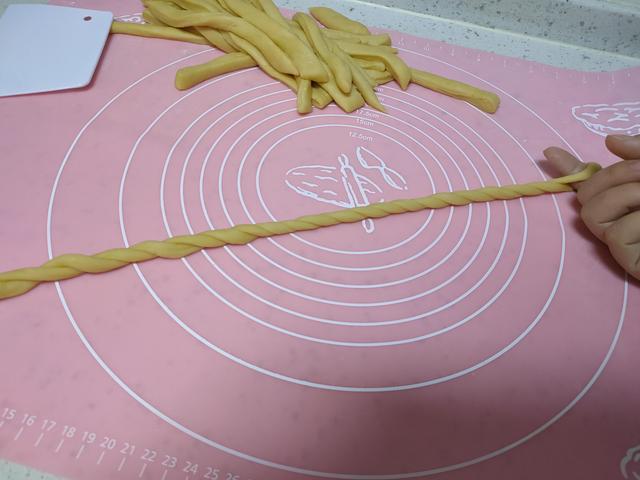 6,拧好以后将首尾两端提起,面条会自动拧成麻花状,把尾端塞到刚刚手指
