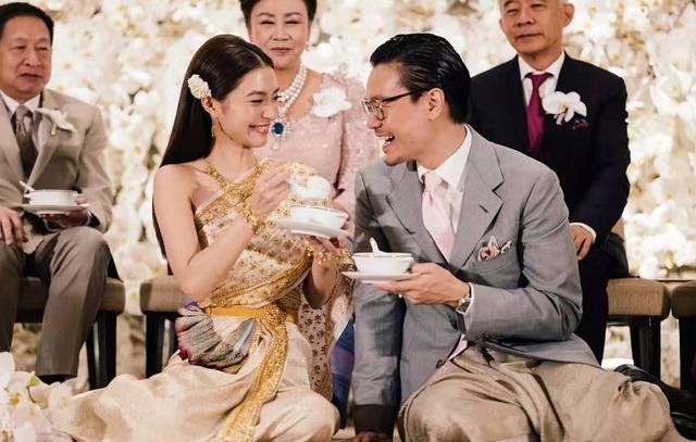 婚礼当天,mew穿着泰式的传统服装,上身是一件斜肩款的丝娃来,以白色