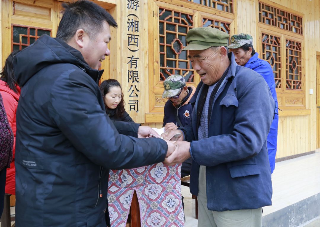 2019年底甘思文(左一)给村民分红多年前,甘思文便与和平村结下不解之