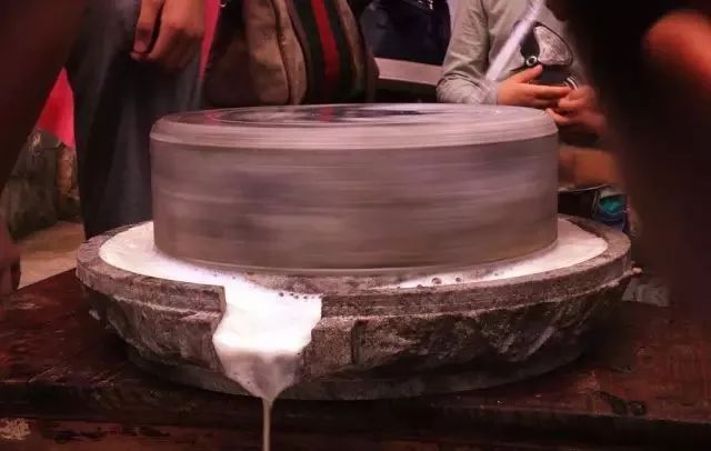 将浸泡过的黄豆,用石磨磨碎,揉沫过箩去渣,煮沸点浆成块,豆腐做成后切