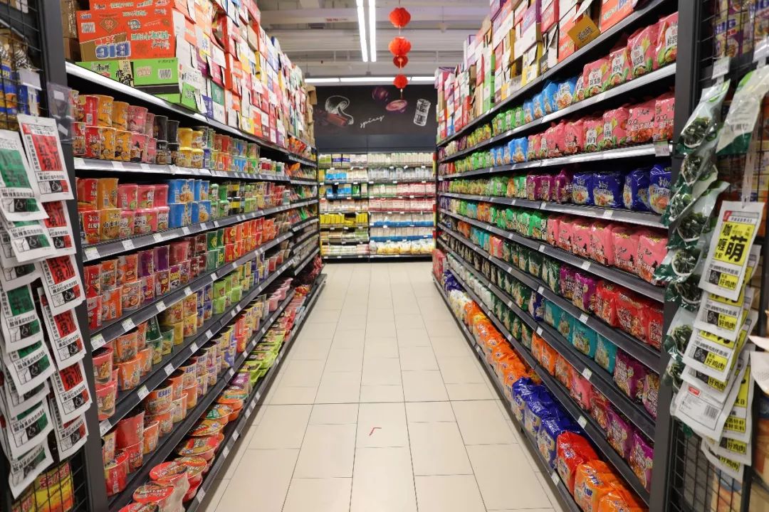 在超市食品区,方便面,矿泉水,肉制品等速食商品摆满货架供消费者选购