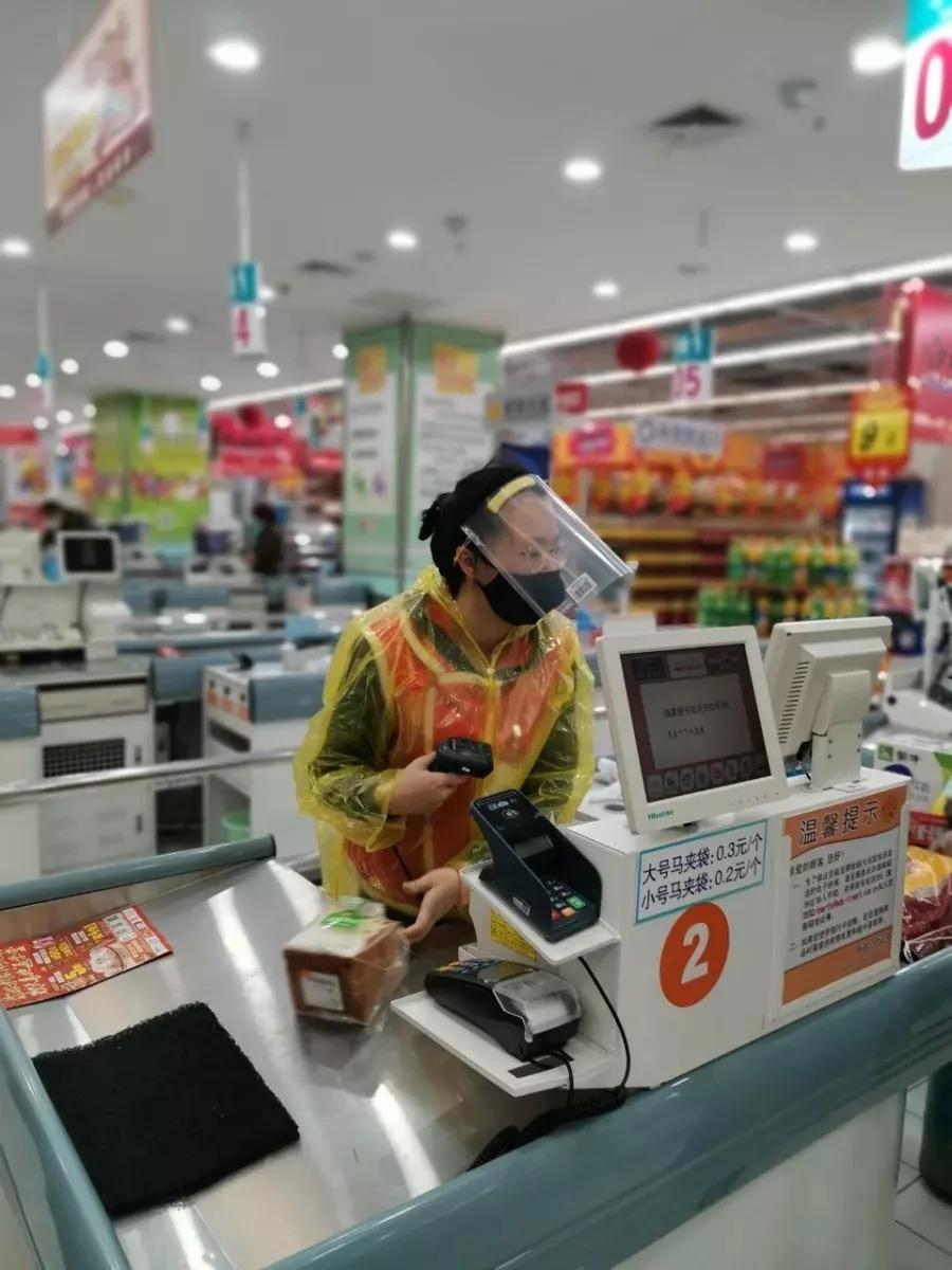 严控超市大门,他们隔着防护面具,用测温枪为每位到场消费的市民测体温