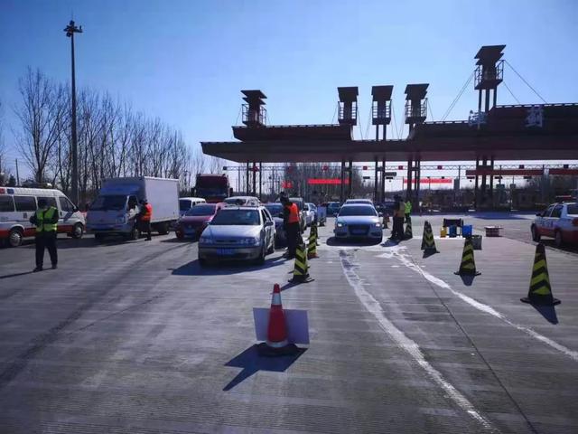 手持测温仪的交通卡口人员在车流中往来穿梭,逢车必查,逢人必检.