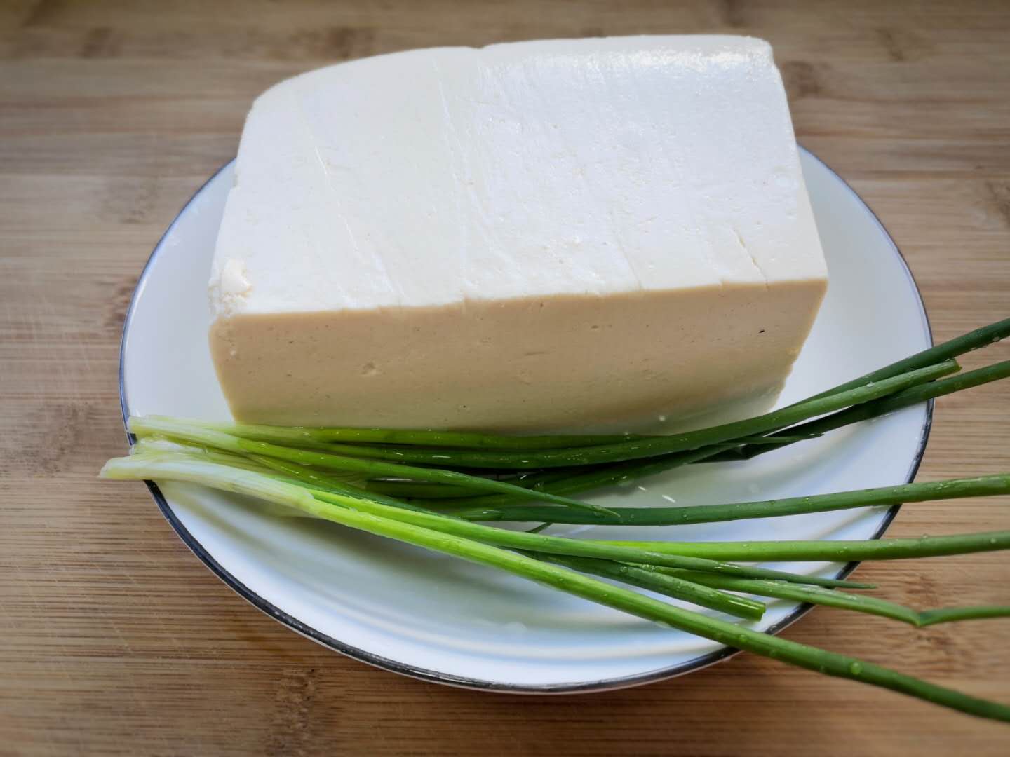 2,豆腐用清水冲洗后,用厨房纸巾把表面水分擦一下,切成薄厚均匀的片.