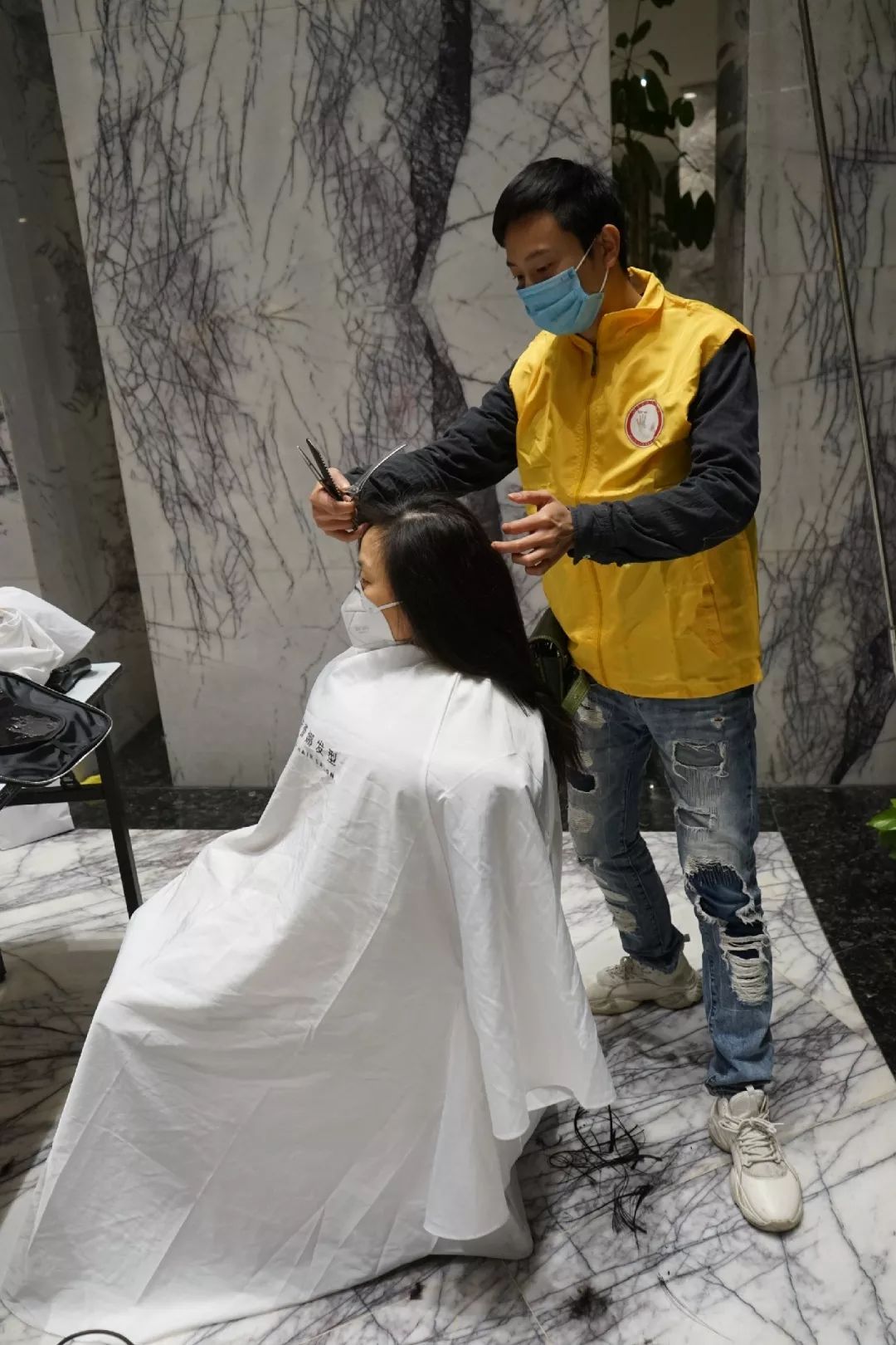 由于设施条件所限遇到身材娇小的医护人员志愿者甚至跪着为她们理发