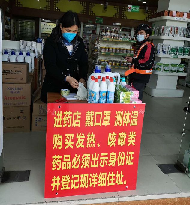 执法人员把"进药店 戴口罩 测体温"等进店要求的警示牌逐一派发到各
