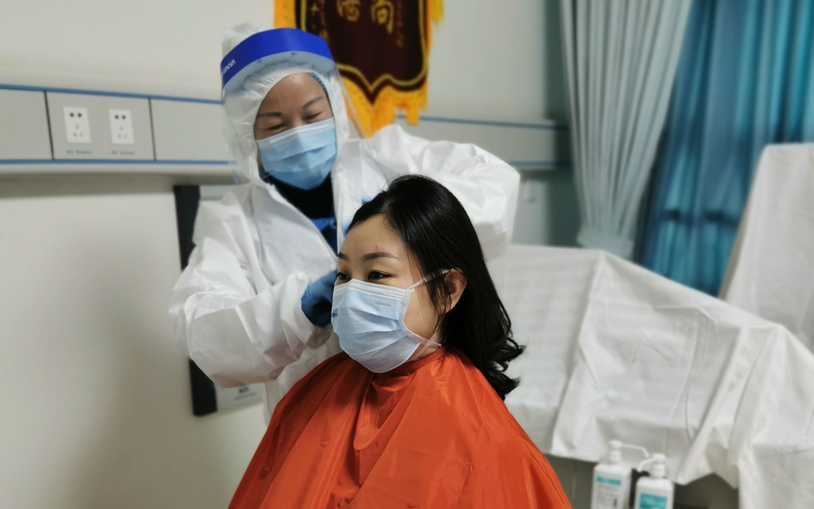 叶丽正在帮一位女医护人员头发剪短