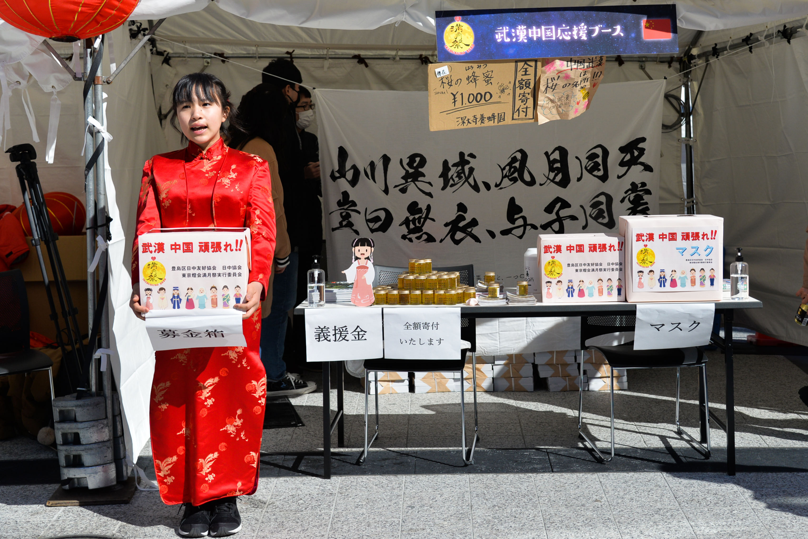 在日本东京池袋,一位身着红色旗袍的日本少女手捧募捐箱为武汉募捐