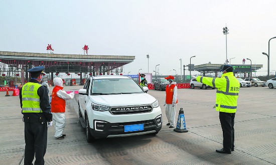 2月13日,在成都高速出口志願者為進入成都的司乘人員測量體溫2月9日