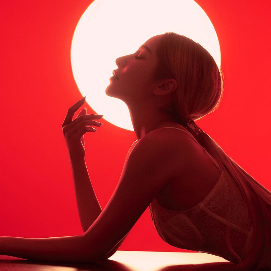 红色光影背景之中她身穿低胸吊带露出锁骨,大秀美肌,身材凹凸有致