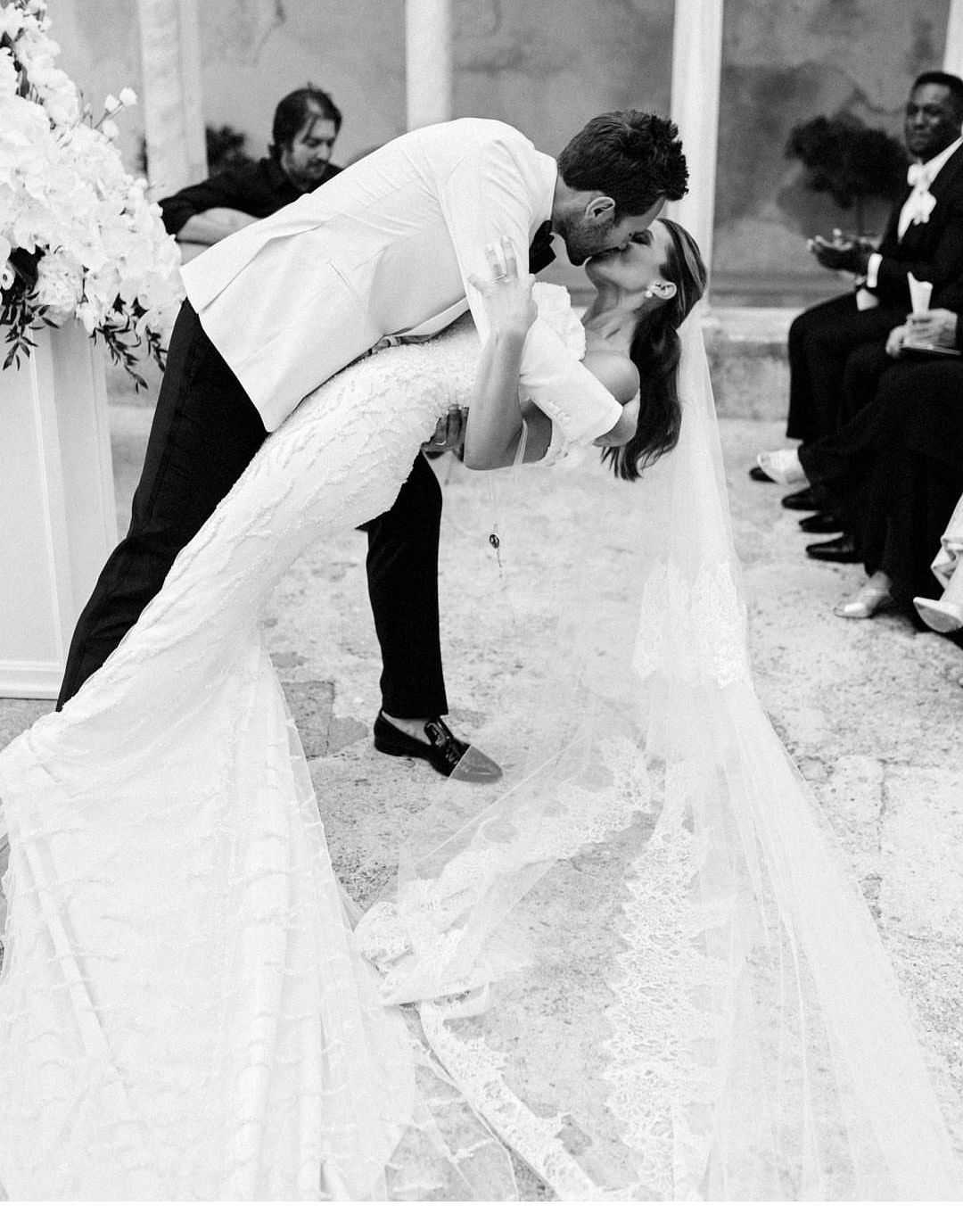 新郎双手抱住新娘的臀部下方,用力托起,新娘靠在新郎胸口,轻轻相吻