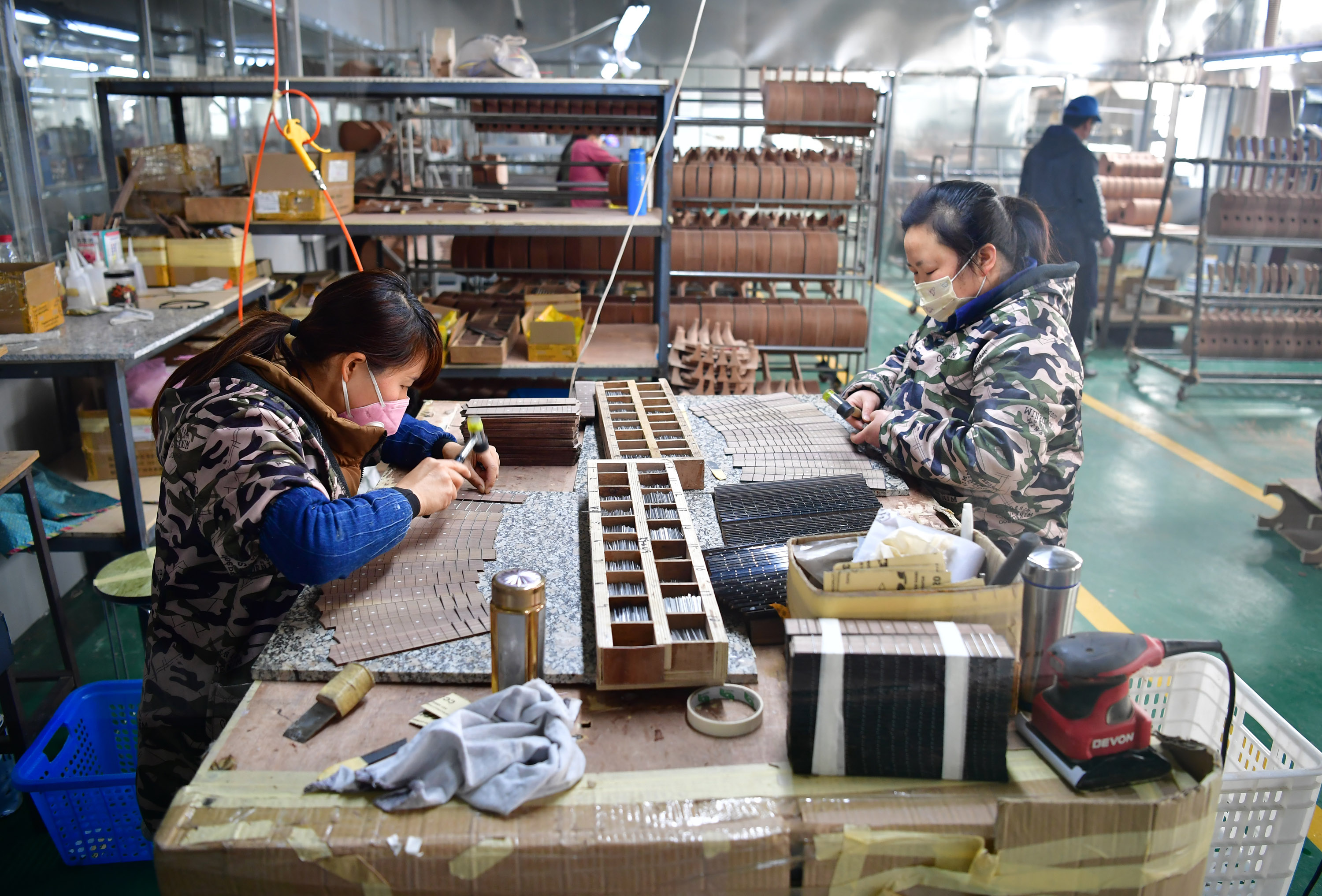 3月12日,在城固縣博望街道辦事處江灣社區一樂器廠車間內,工人在製作