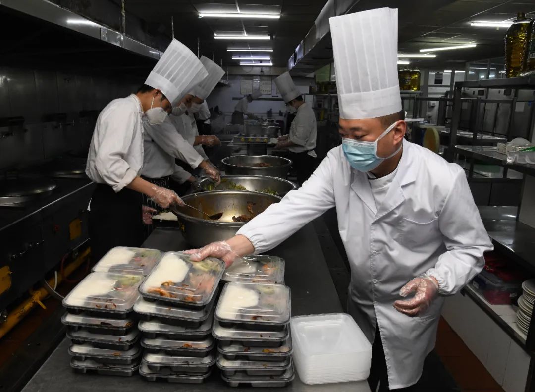 为避免扎堆聚餐,青岛一餐饮企业后厨工作人员在制作团体订餐的盒饭 李