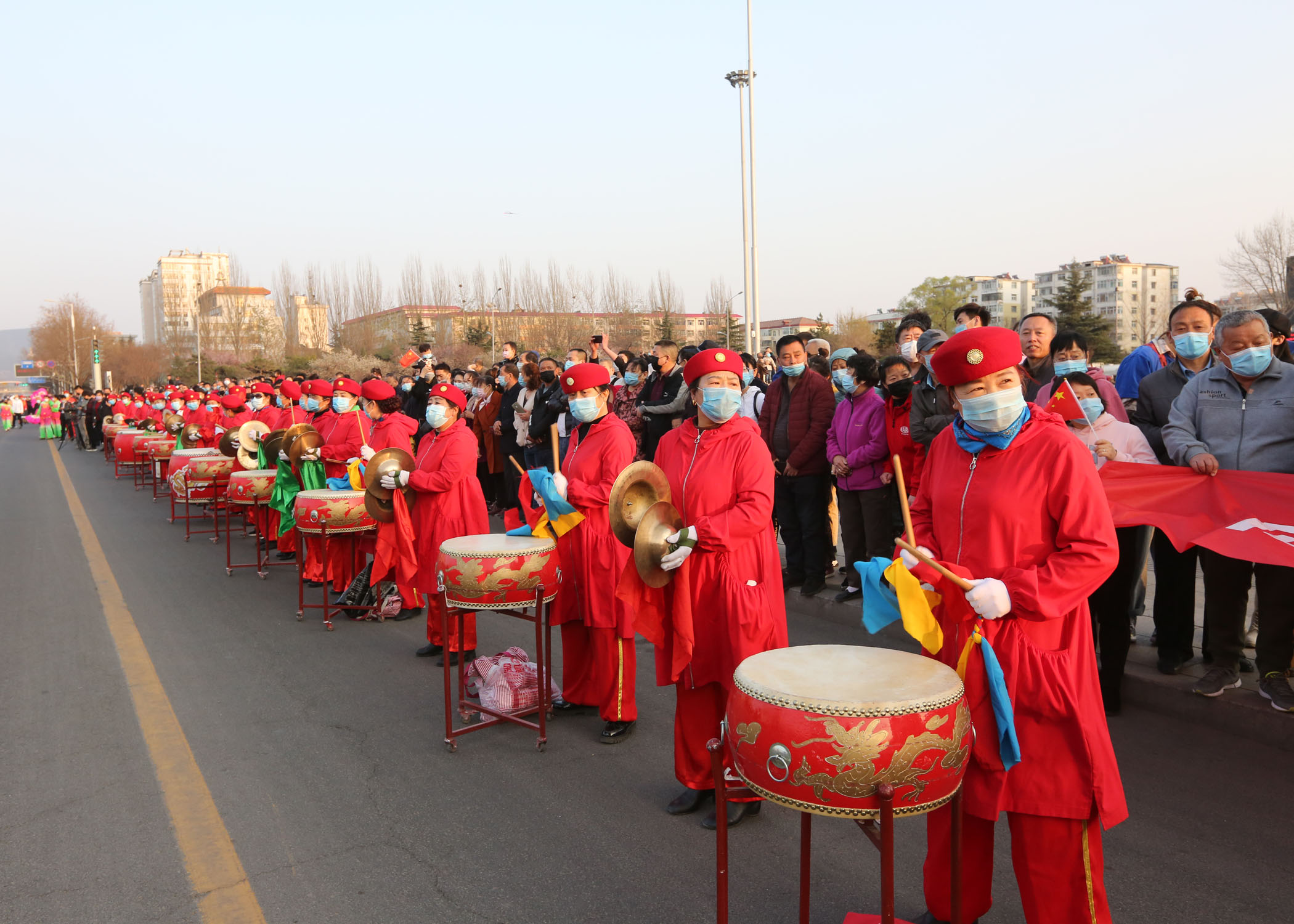 道路两侧,沿途市民们自发组织拉起横幅,敲响锣鼓,手挥国旗热烈欢迎