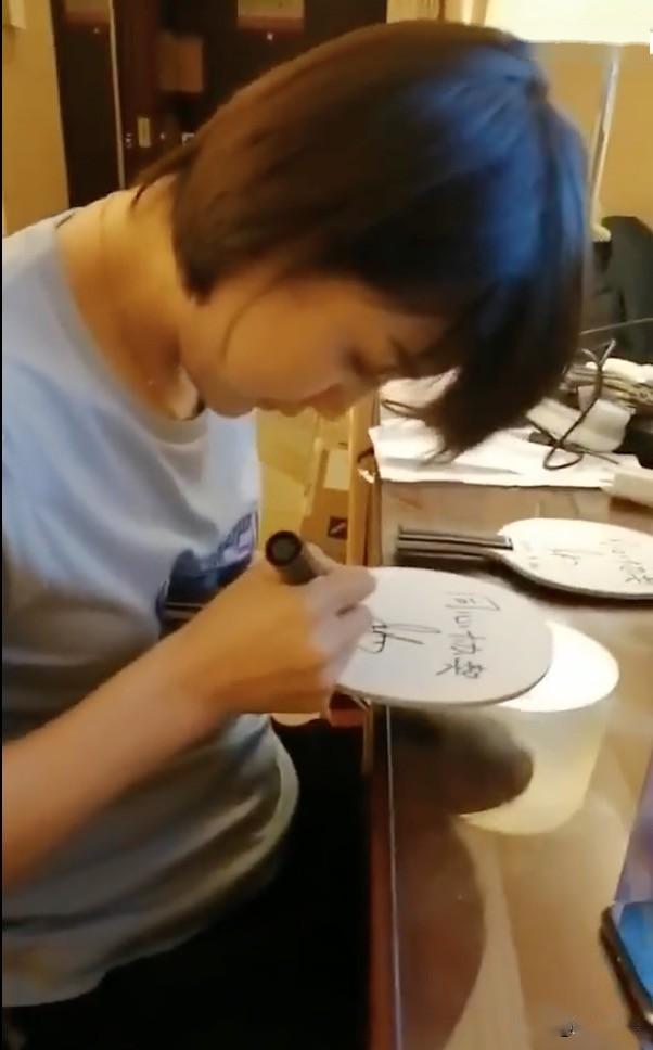 朱雨玲把底板放在腿上,签名也是潇洒自得.