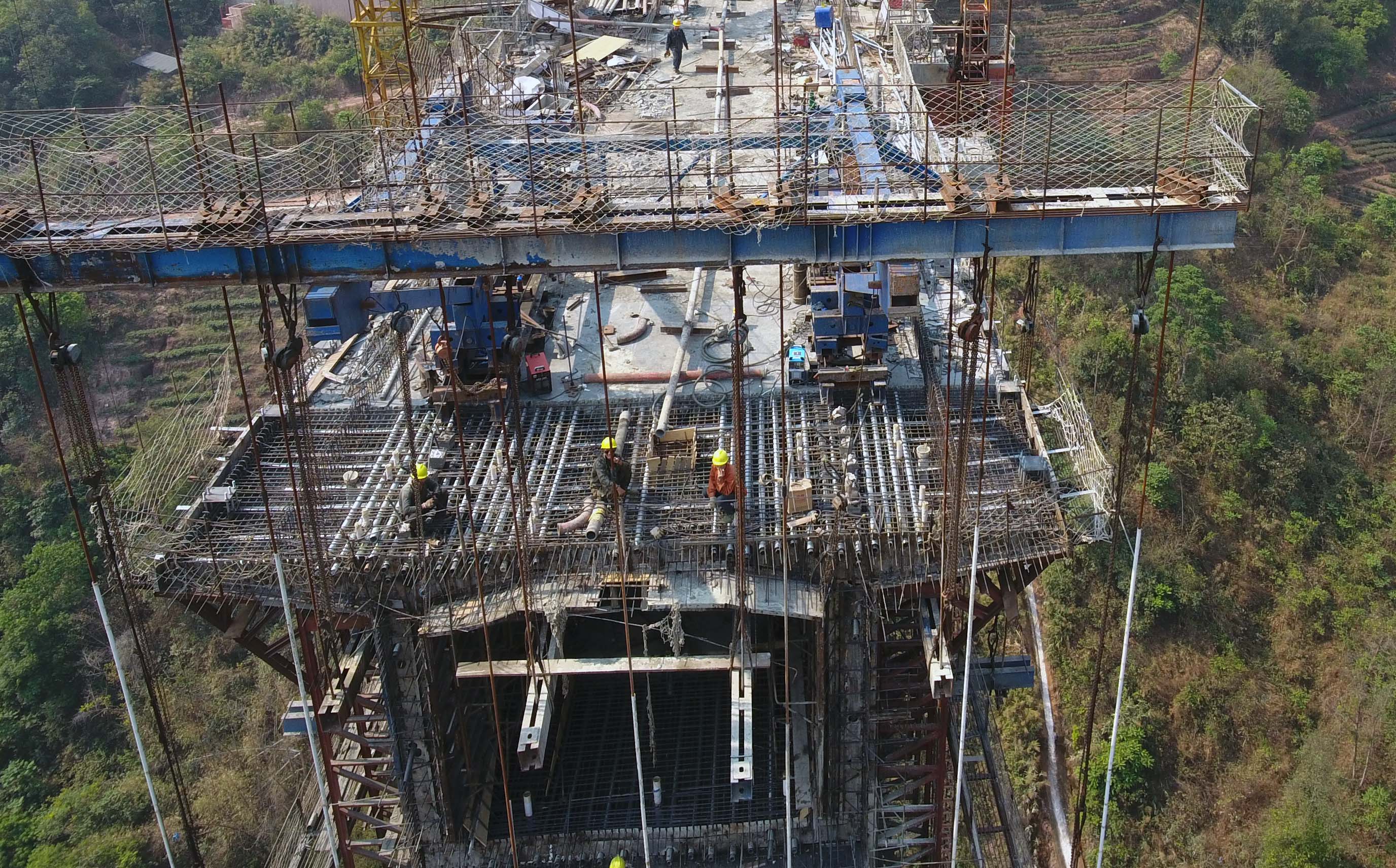 4月6日,建設者在夕陽下的玉磨鐵路那蘇河大橋上施工.