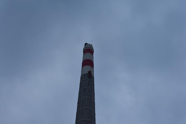 海南包工头欠债后爬上40米高烟囱轻生消防民警合力救援