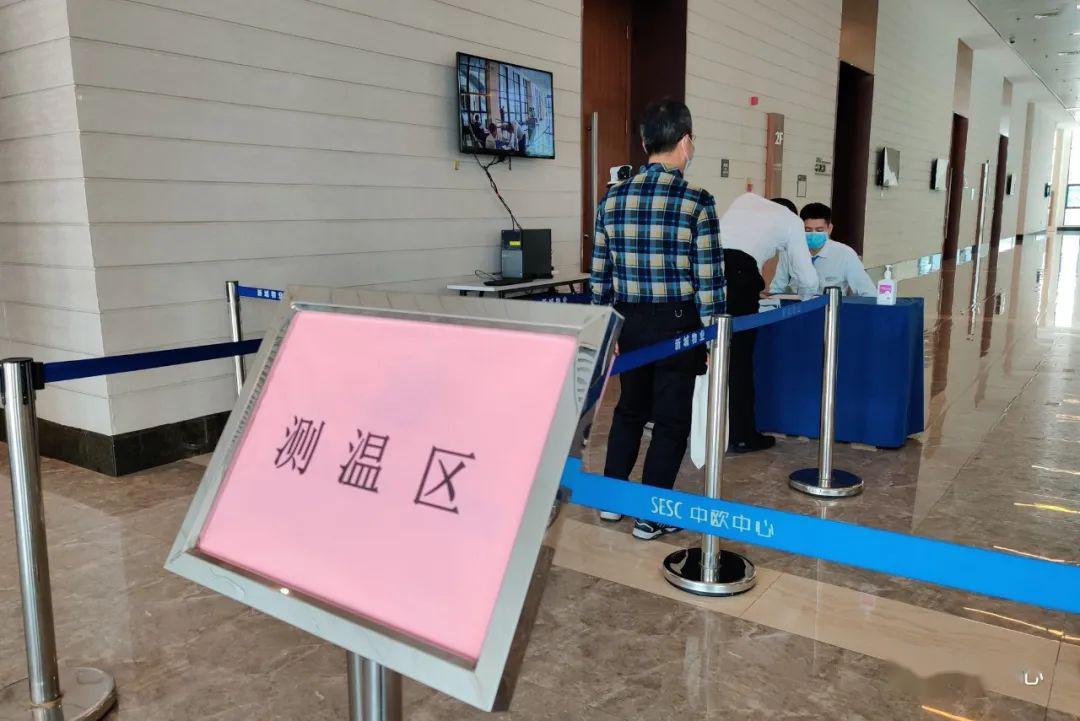 参会人员在会议室入口的体温监测点有序排队进行测温.
