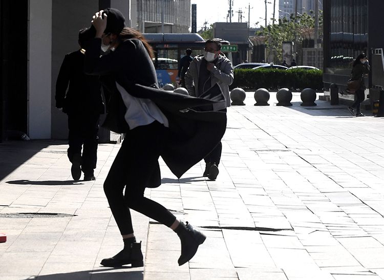 市民迎风出行,衣服被吹起来了.市民在大风中出行.