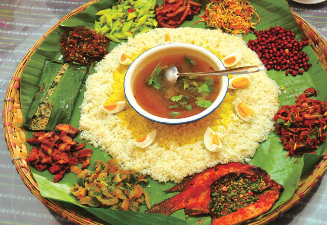 一只圆形簸箕,铺上芭蕉叶中间放一碗杂菜汤,汤外是米饭米饭外围一圈菜