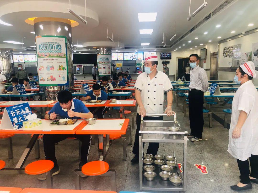 育新学校的学生间隔一米排队到食堂,洗手,测温后依次分开入座,专人