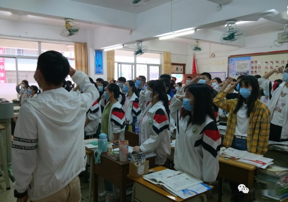 化州三中校领导指导学生有序通过测温门进入校园.