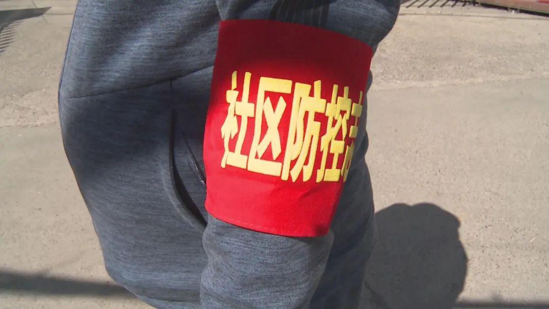 在小区卡口,志愿者们佩戴口罩,红袖标,坚守着岗位,对小区出入人员