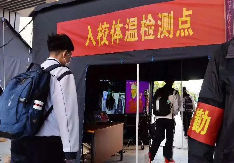 们保持一米间隔,戴着口罩依次排队进校,按照指定路线通过红外线测温