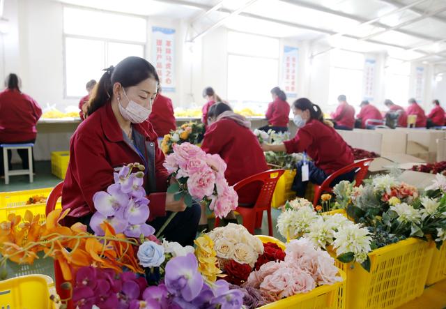 记者在段家镇西河村村镇工厂车间看到,20多名妇女在灵巧地组装仿真花