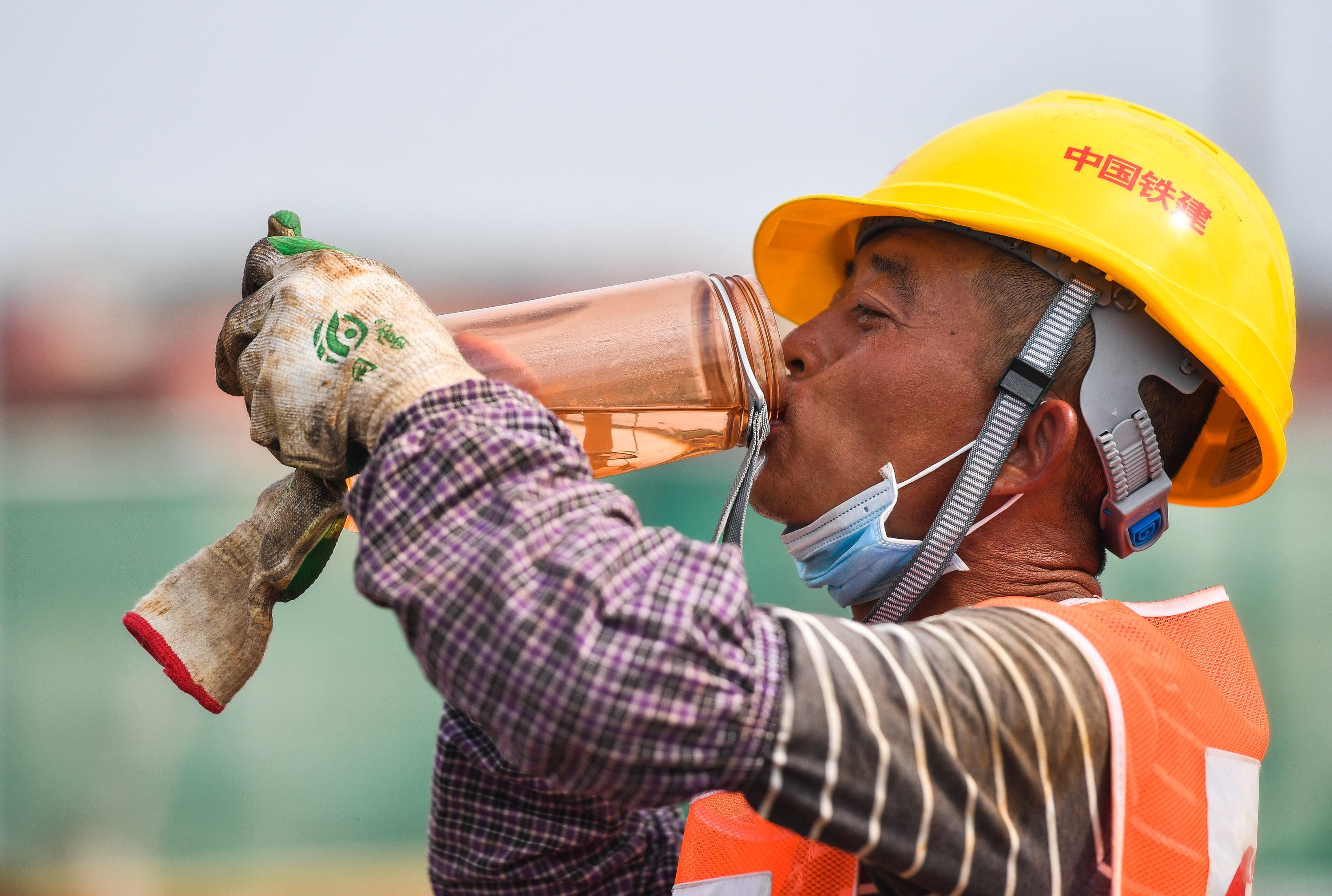 5月1日,在广州地铁18号线陇枕停车场建设现场,建设工人大口喝水