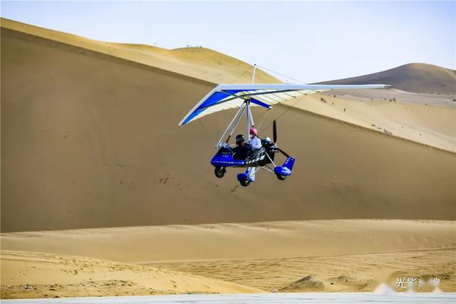 五一敦煌直升机滑翔机在鸣沙山月牙泉上空自由飞翔