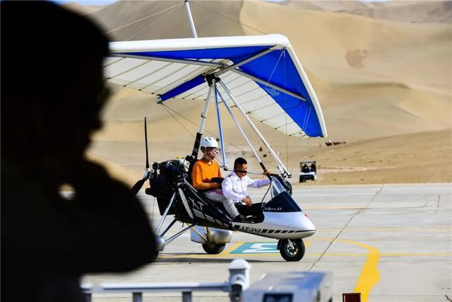 五一敦煌直升机滑翔机在鸣沙山月牙泉上空自由飞翔