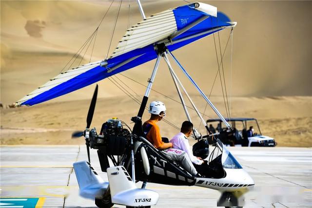 五一敦煌直升机滑翔机在鸣沙山月牙泉上空自由飞翔