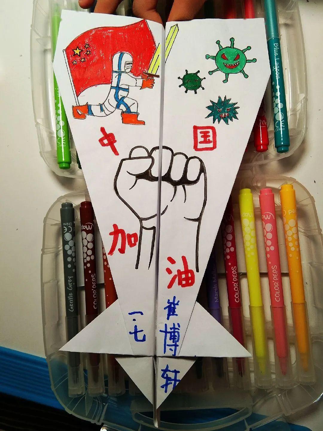 一,二年级学生折叠创意纸飞机,并在纸飞机上完成以抗击新型冠状病毒