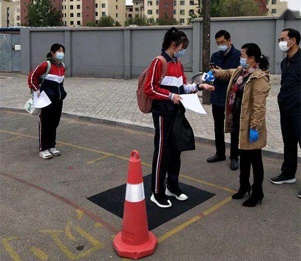 锦州十八中学生4个班级一组,保持一米以上间隔,有序通过红外线测温仪