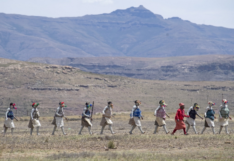 12月6日,在莱索托首都马塞卢,一群身穿传统服饰的莱索托人沿道路行走