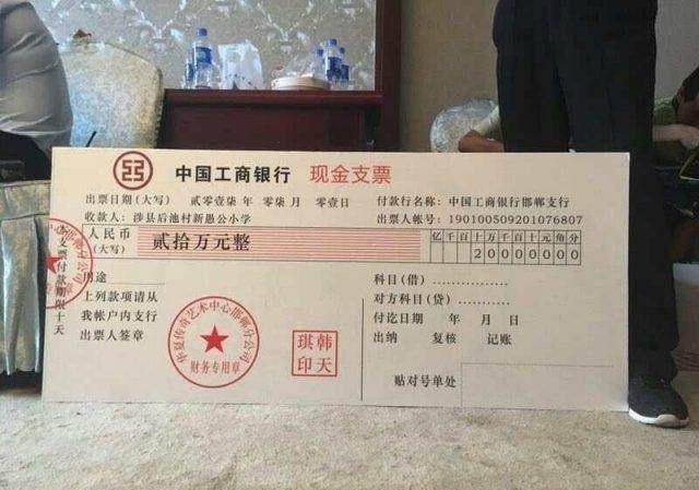 一家单位将写有20万元的现金支票模型送到校领导手中