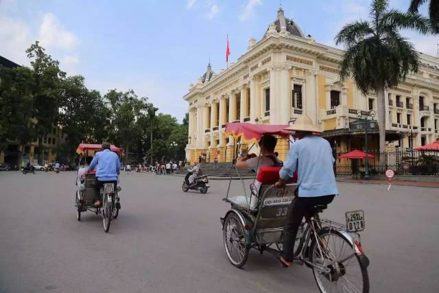 三輪車遊三十六行古街,右側建築越南國家大劇院.