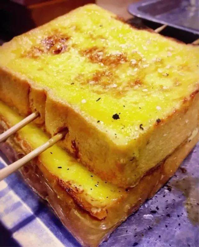 烤面包片,上面涂炼乳烤一下很香甜,橘黄色看上去好好吃的样子~~烤串吃