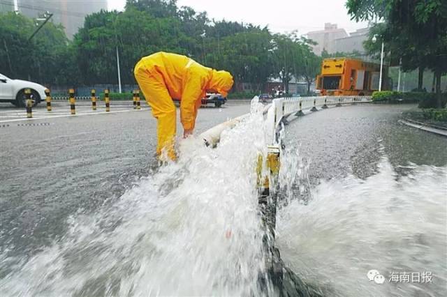 海口金牛路口附近出现大面积积水,市排水管道养护所的工作人员正在