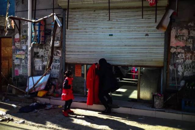 新建村内,一位女店主一手提着崭新的红色大衣,一边躬身拉下卷帘门