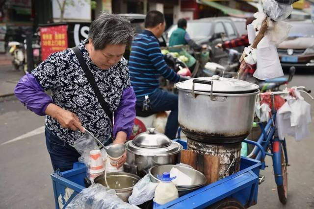 骑着三轮车的阿姨悠悠地为顾客盛起一杯香浓的豆浆汁.